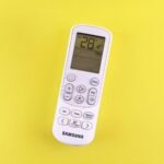 Persona ajustando un aire acondicionado por hora con mando a distancia
